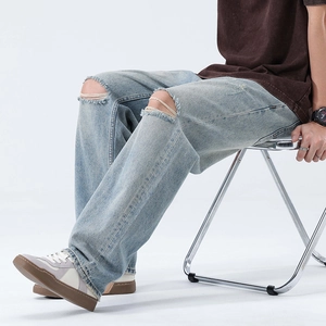 Men's light blue distressed wide leg jeans with ripped knees in a street casual style