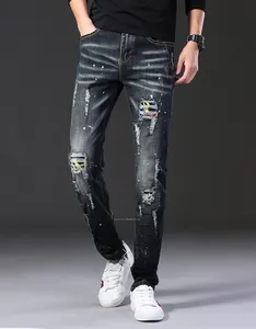 Détail d'un jean pour homme délavé avec taches de peinture et écussons colorés