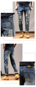 Detail view of denim patches with red-white stripes and leather brand tag on jeans