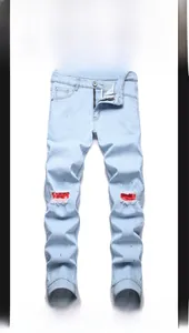 Detail of ripped blue jeans with red printed fabric lining and paint splatter accents