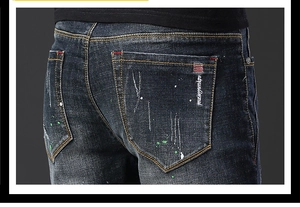 Gros plan sur le jean bleu avec taches de peinture et surpiqûres sur la poche arrière