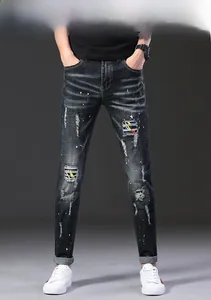 Détail de jean slim délavé avec des taches de peinture et des patchs colorés