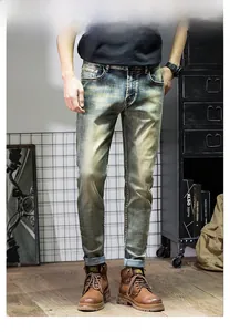 Detail of men's slim fit jeans featuring vintage mud wash and whiskered denim texture
