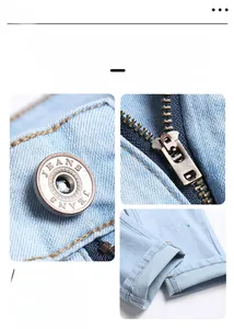 Detailed close-up of metal button, zipper and hem stitching on light blue denim jeans