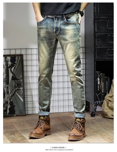Detail of slim fit vintage washed jeans styled with work boots in industrial setting