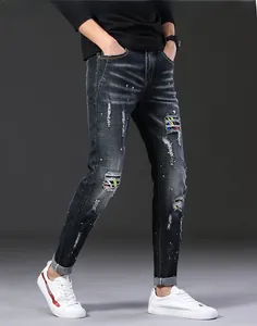 Détails de jeans déchirés montrant des patchs colorés et des taches de peinture blanche