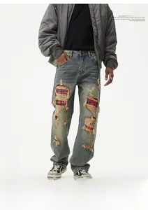 Detail shot of men's distressed jeans featuring vintage rips with red plaid patch lining