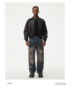 Zerstörte dunkelblaue Jeans mit Rissen kombiniert mit brauner Leder-Fliegerjacke