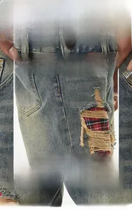 Detail of light blue distressed jeans featuring red plaid patchwork inside knee rips