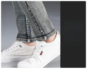 Detailed close-up of men's slim-fit denim jeans cuff paired with white embossed casual shoes