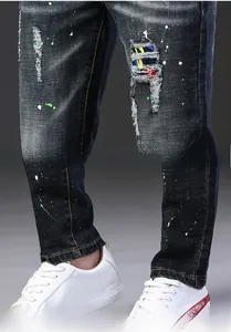 Vue détaillée du jean slim pour homme avec déchirures, taches de peinture et patch