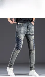 Detail of slim fit men's distressed blue jeans with patchwork fabric and decorative zippers
