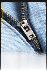 Detailed macro view of the vintage bronze metal zipper on light blue washed denim jeans