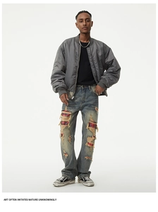 Detail of distressed denim pants with red plaid patches and vintage wash for men