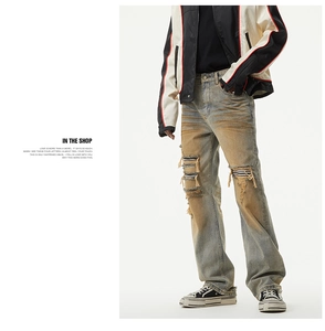 Detail of distressed ripped jeans featuring vintage wash and striped inner patch layer