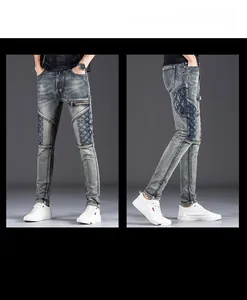 Detail of slim fit men's distressed patchwork jeans with metal zipper and wash effect