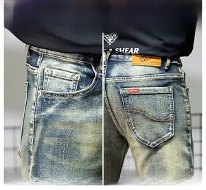 Detailed macro view of vintage washed denim jeans showing reinforced pockets and leather patch