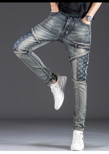 Detail of slim fit men's patchwork denim jeans with ethnic embroidery and metal zipper
