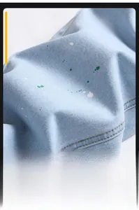 Macro view of light blue denim fabric featuring white and green paint splatter detail