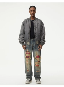 Detail of loose-fit distressed jeans with red plaid patches and vintage blue wash