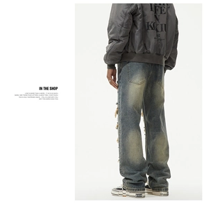Detail view of vintage washed blue jeans with distressed rip and thread patch craftsmanship