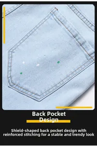 Detail of light blue denim back pocket with green paint splatter and orange stitching