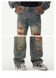 Close-up of vintage distressed jeans with red plaid patches and destroyed denim details
