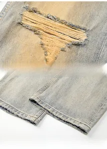 Detail view of retro washed denim jeans featuring distressed ripped holes and stitched hems