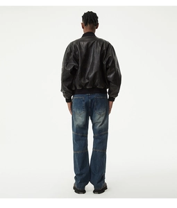 Détail d'un blouson aviateur en cuir vintage avec un jean en denim indigo délavé à coupe droite