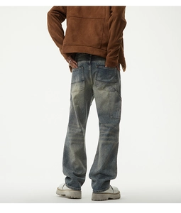 Detail view of vintage washed blue denim pants with back pockets and worn-out distressed effects