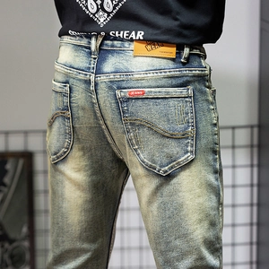 Retro vintage slim-fit men's blue jeans with wash effects and premium leather waist patch