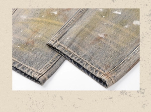 Detail shot of vintage distressed jeans with yellow mud stains and white paint splatters