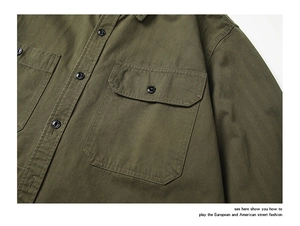 Détail d'une chemise en coton vert armée avec deux poches poitrine et des boutons noirs