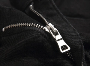 Macro shot of durable silver metal zipper and black twill denim fabric texture detail
