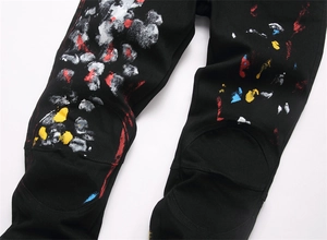 Close-up of black streetwear pants featuring colorful artistic paint splatter and stitching