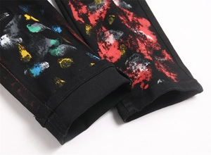 Close-up of black street style jeans with colorful paint splatter and side zipper detail