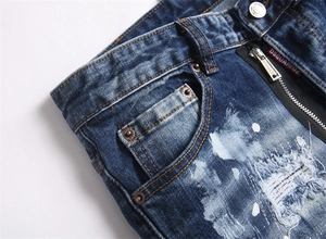 Detailed macro view of distressed denim jeans with paint splatters and branded red tag