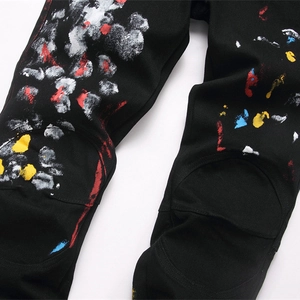 Men's black street-style distressed jeans featuring colorful paint splatter and knee stitching