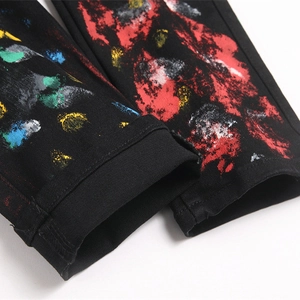 Street style black denim jeans with artistic multicolor paint splatter detail on cuff