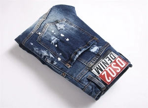 Detailed close-up of distressed denim texture with white paint splatters and logo patch