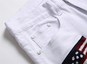 Detail of white denim jeans featuring embroidered American flag patch and metal rivets