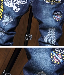 Detailed close-up of heavy embroidery and vintage patches on blue streetwear jeans