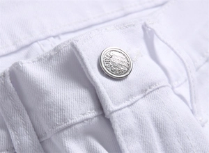 Macro detail of silver metal button with Jeans Wear engraving on white denim jeans
