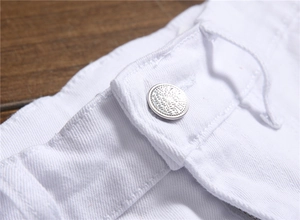Close-up of white denim fabric featuring a silver metal button with engraved lettering