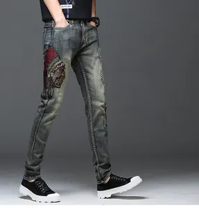 Détail de la broderie indienne colorée et du denim vieilli sur un jean bleu slim