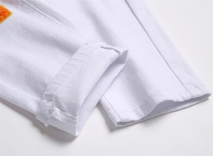 Macro detail of white twill cotton trouser hem with precise stitching and yellow patch