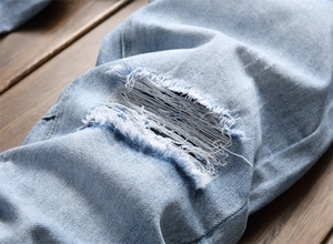 Gros plan sur un jean bleu clair délavé avec des détails effilochés et déchirés