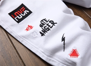 Detailed view of white cotton street style pants with embroidered patches and graphic text