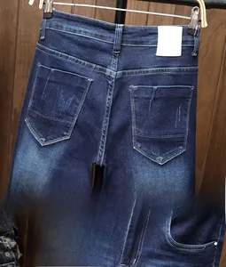 Detail of tiger embroidery and distressed wash effects on dark blue street jeans