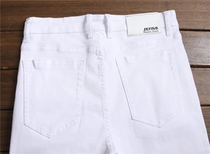 Close-up of white denim jeans featuring back pockets and leather brand tag on waistband